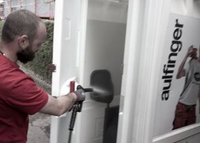 Mitarbeiter reinigt Toilettenkabine von innen mit Hochdruckreiniger