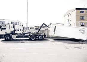 Weißer Aulfinger Abroller lädt weißen Abrollcontainer der Firma Jörg Aulfinger GmbH & Co. KG ab
